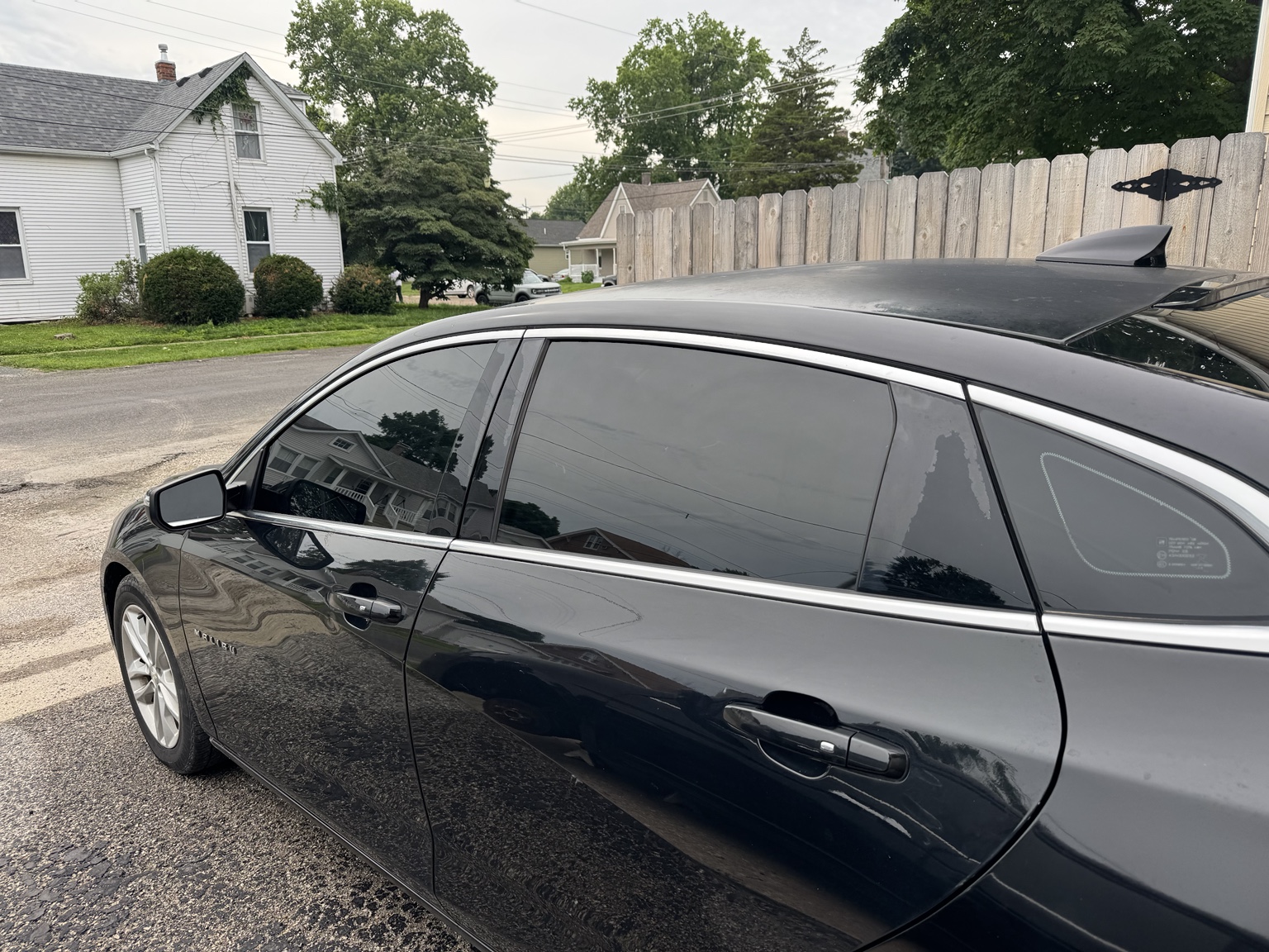Driver-side view of black 2018 Chevrolet Malibu with dark carbon tint on the side windows