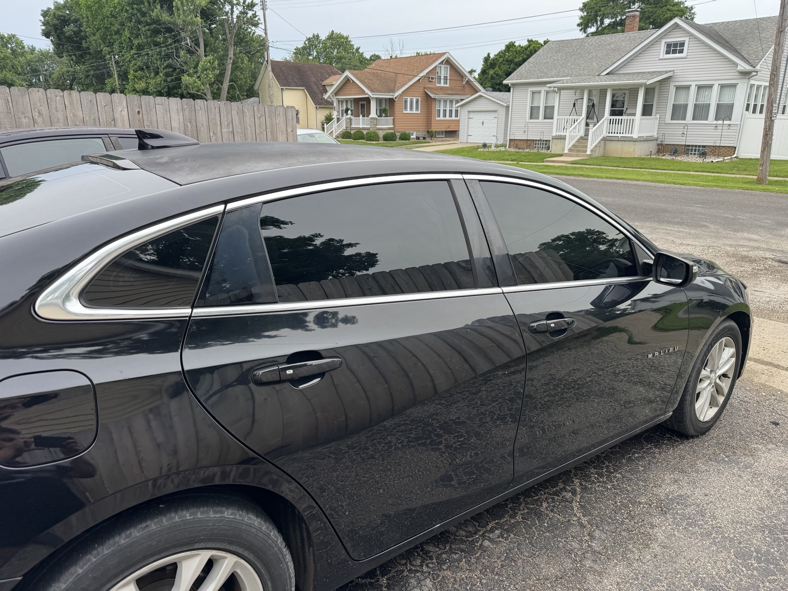 Passenger-side view of black 2018 Chevrolet Malibu with dark carbon tint on the side windows